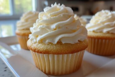 Close-up of a vanilla cupcake topped with perfectly piped, creamy vanilla buttercream frosting.