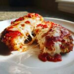 Two pieces of Easy Chicken Parmesan being pulled apart, showing melted mozzarella cheese strings.