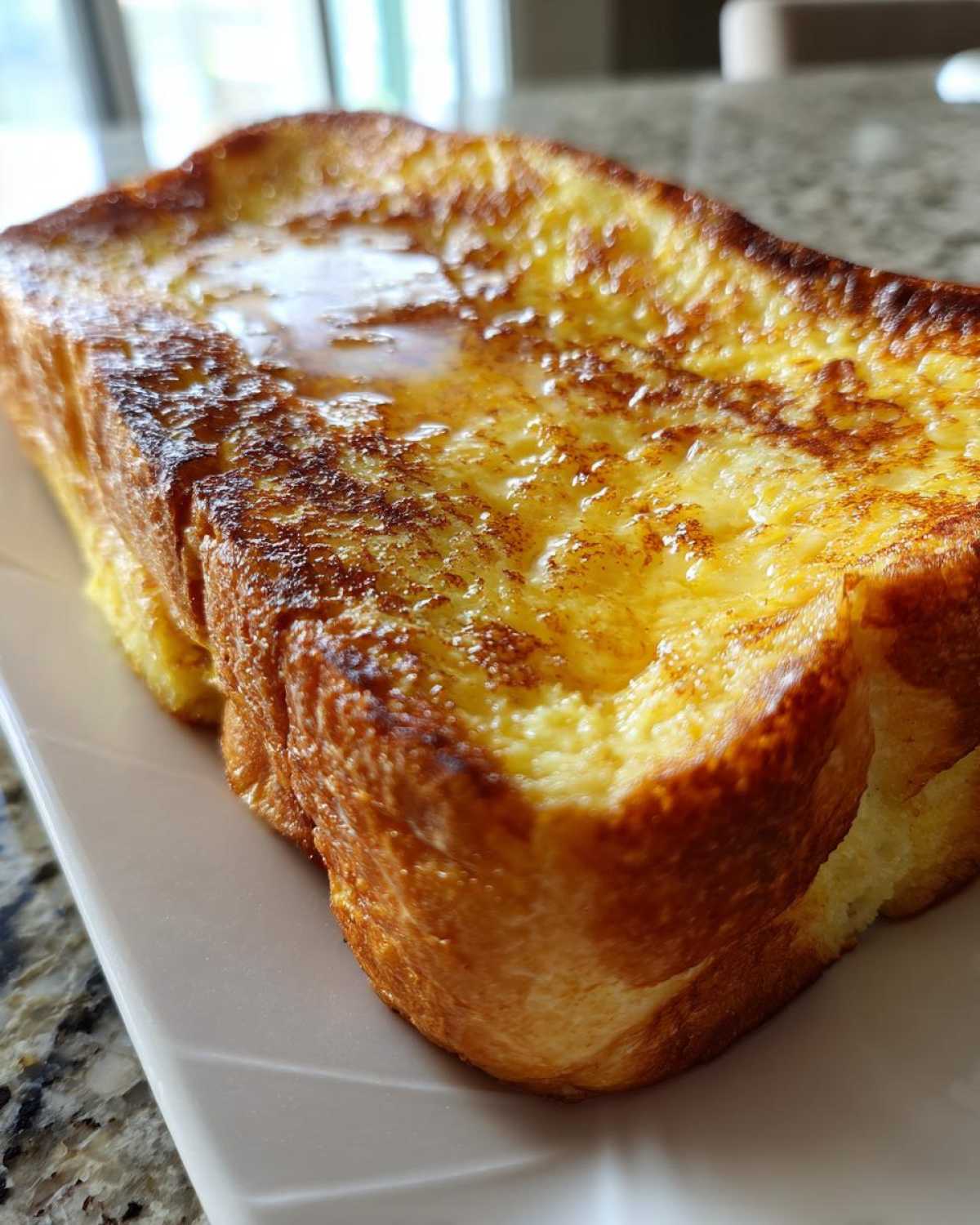 Close-up of a thick slice of golden brown easy french toast drizzled with syrup.