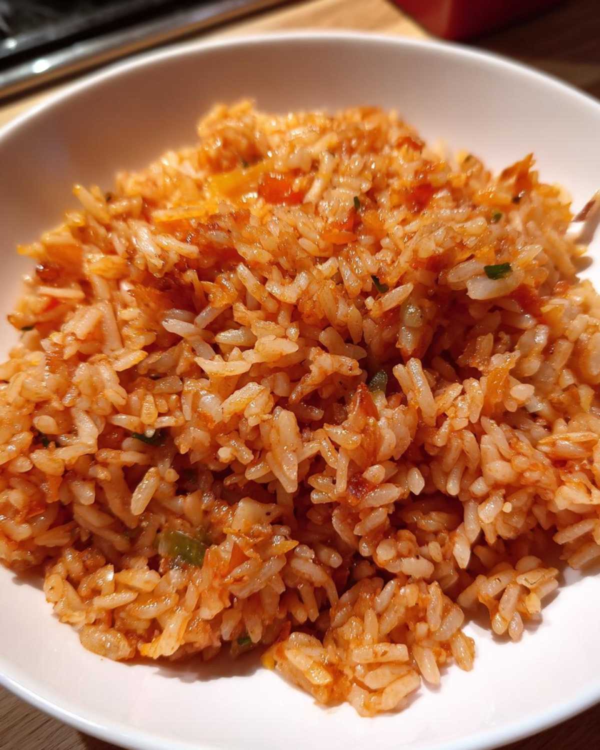 Close-up of fluffy, seasoned orange-red Spanish rice served in a white bowl.