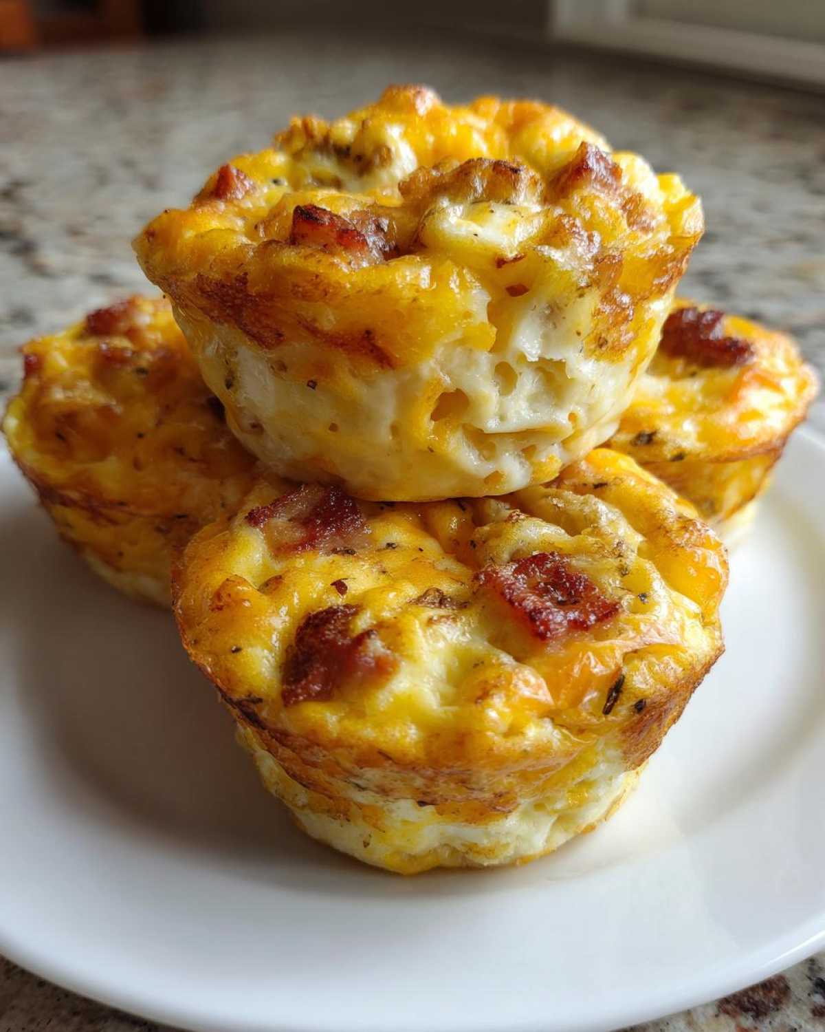 A stack of four fluffy bacon muffin tin egg bites showing golden tops and cheesy texture.