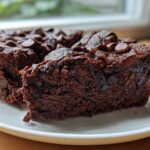 Close-up of two fudgy black bean brownies topped with melted chocolate chips on a white plate.