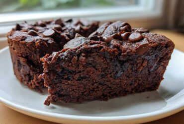 Close-up of two fudgy black bean brownies topped with melted chocolate chips on a white plate.