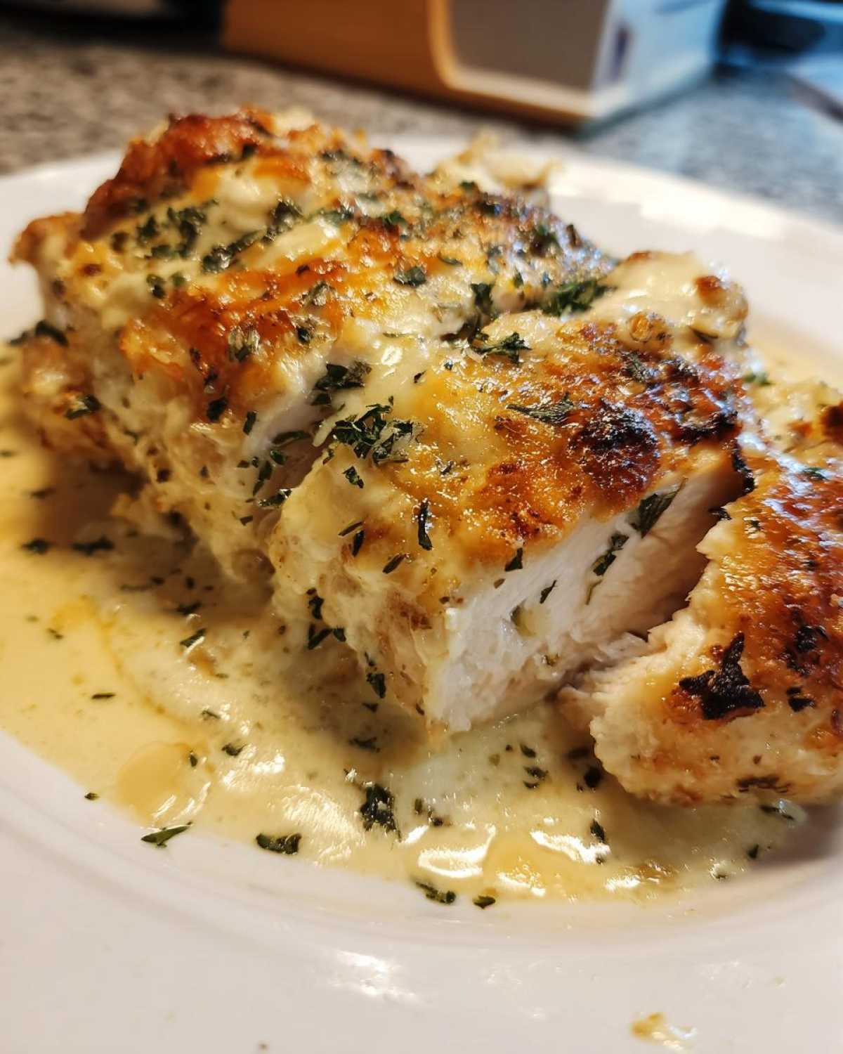 Close-up of sliced Garlic parmesan chicken bake covered in creamy sauce and herbs.
