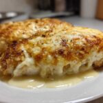 Close-up of two servings of Garlic parmesan chicken bake covered in melted, browned cheese sauce.