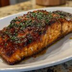 A perfectly cooked, glazed baked salmon fillet topped with fresh chopped parsley served on a white platter.
