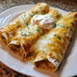 Three delicious green chile chicken enchiladas covered in melted cheese and sour cream.