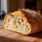 Close-up of a freshly baked Italian bread cut in half showing an open, airy crumb structure and a golden, crispy crust.