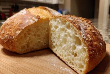 Close-up of a freshly baked Italian bread loaf cut in half, showing an open, airy crumb structure and golden crust.