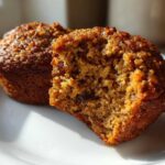 Close-up of a bran muffin cut in half showing its moist, textured interior and raisins.