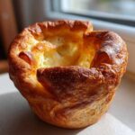 A single, beautifully risen, golden-brown yorkshire pudding with crispy edges and a hollow center.