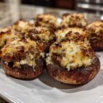Close-up of several perfectly baked Sausage stuffed mushrooms topped with melted, browned cheese.