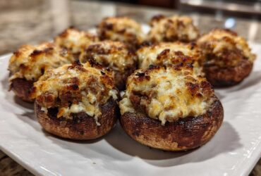 Close-up of several perfectly baked Sausage stuffed mushrooms topped with melted, browned cheese.