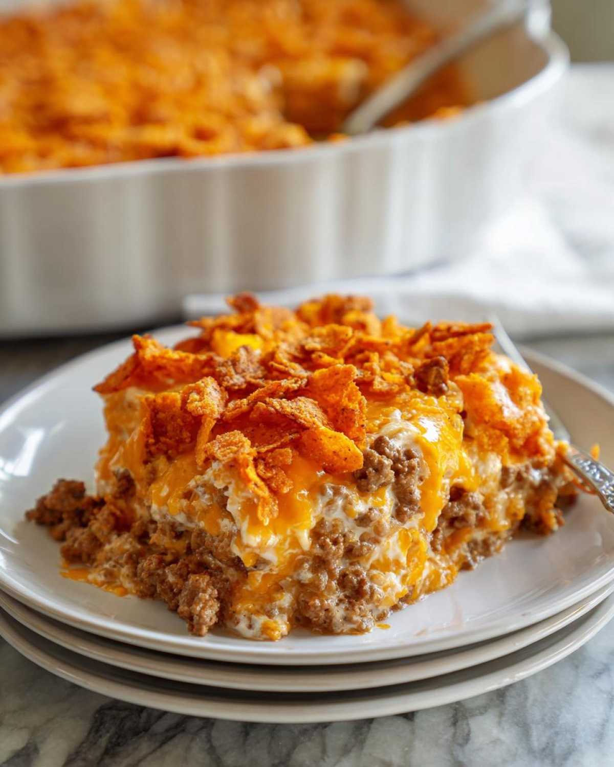 A generous serving of Dorito Casserole featuring layers of ground beef, creamy sauce, melted cheese, and a crunchy Dorito topping.