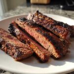 Four slices of medium-rare steak, showing a dark char and juicy interior, prepared with carne asada marinade.