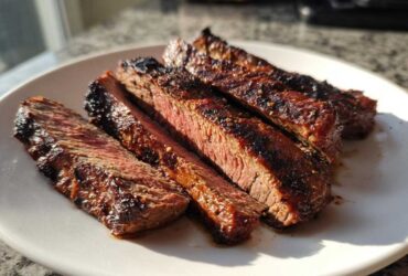 Four slices of medium-rare steak, showing a dark char and juicy interior, prepared with carne asada marinade.