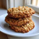 A stack of three golden brown, chewy oatmeal cookie treats resting on a white plate.