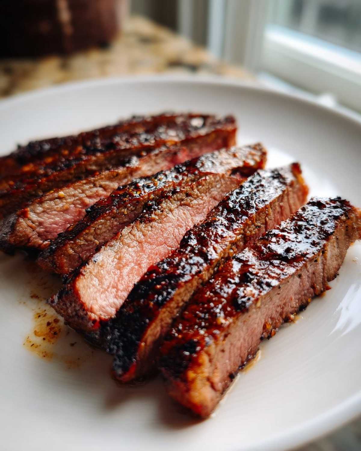 Close-up of medium-rare steak slices showing a dark, glazed crust from the Carne asada marinade.