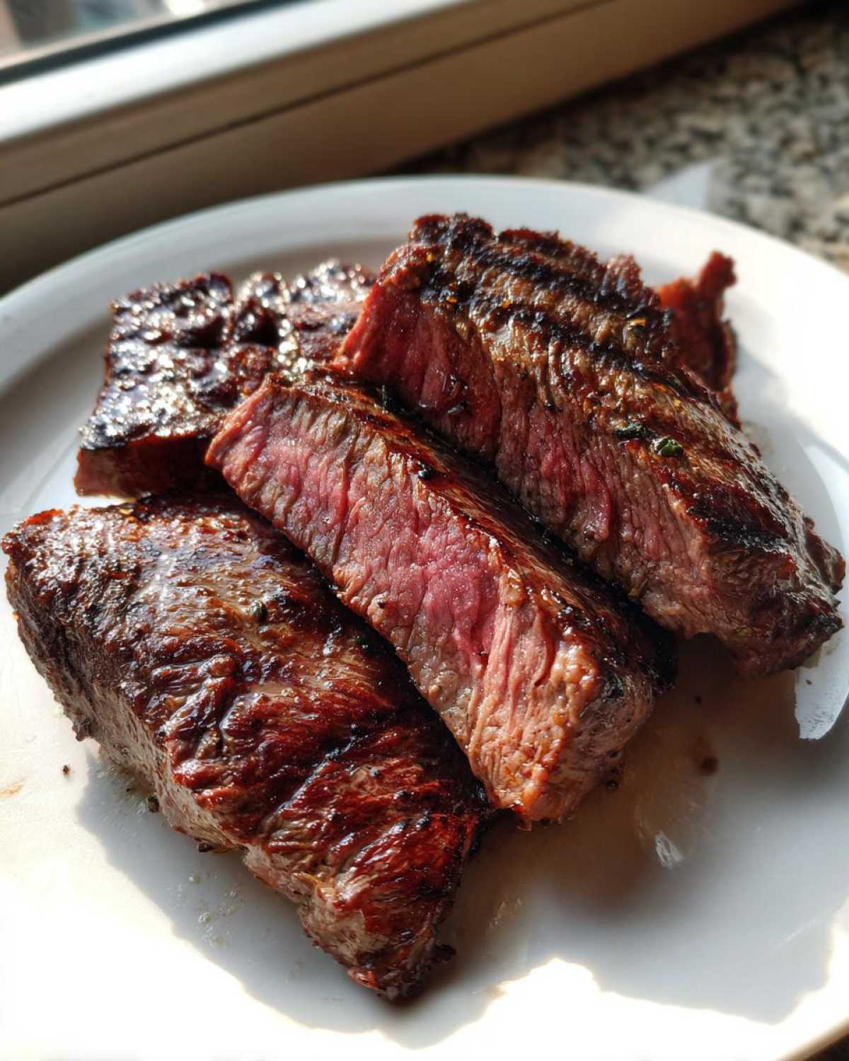 Close-up of medium-rare steak slices showing a juicy pink center, likely prepared with a carne asada marinade.