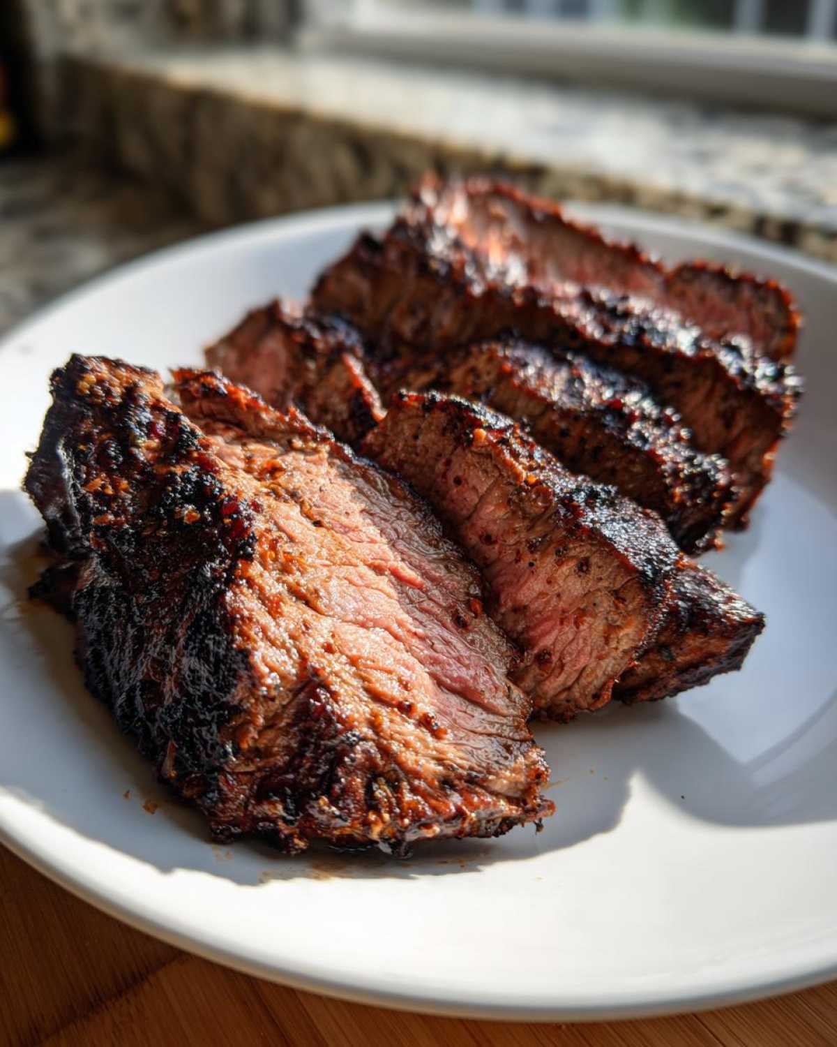 Close-up of medium-rare steak slices showing a dark char from grilling, achieved with a great carne asada marinade.