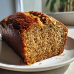 Close-up of a moist slice of sugar free banana bread showing its golden-brown crust and soft crumb texture.