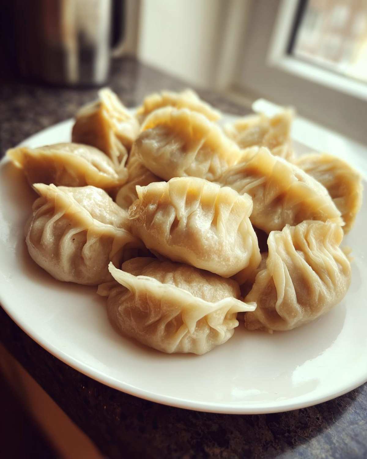 A close-up of several freshly steamed Traditional Chinese Dumplings piled on a white plate.
