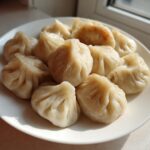 A plate filled with freshly steamed Traditional Chinese Dumplings, showing pleated wrappers and one slightly pan-fried dumpling.