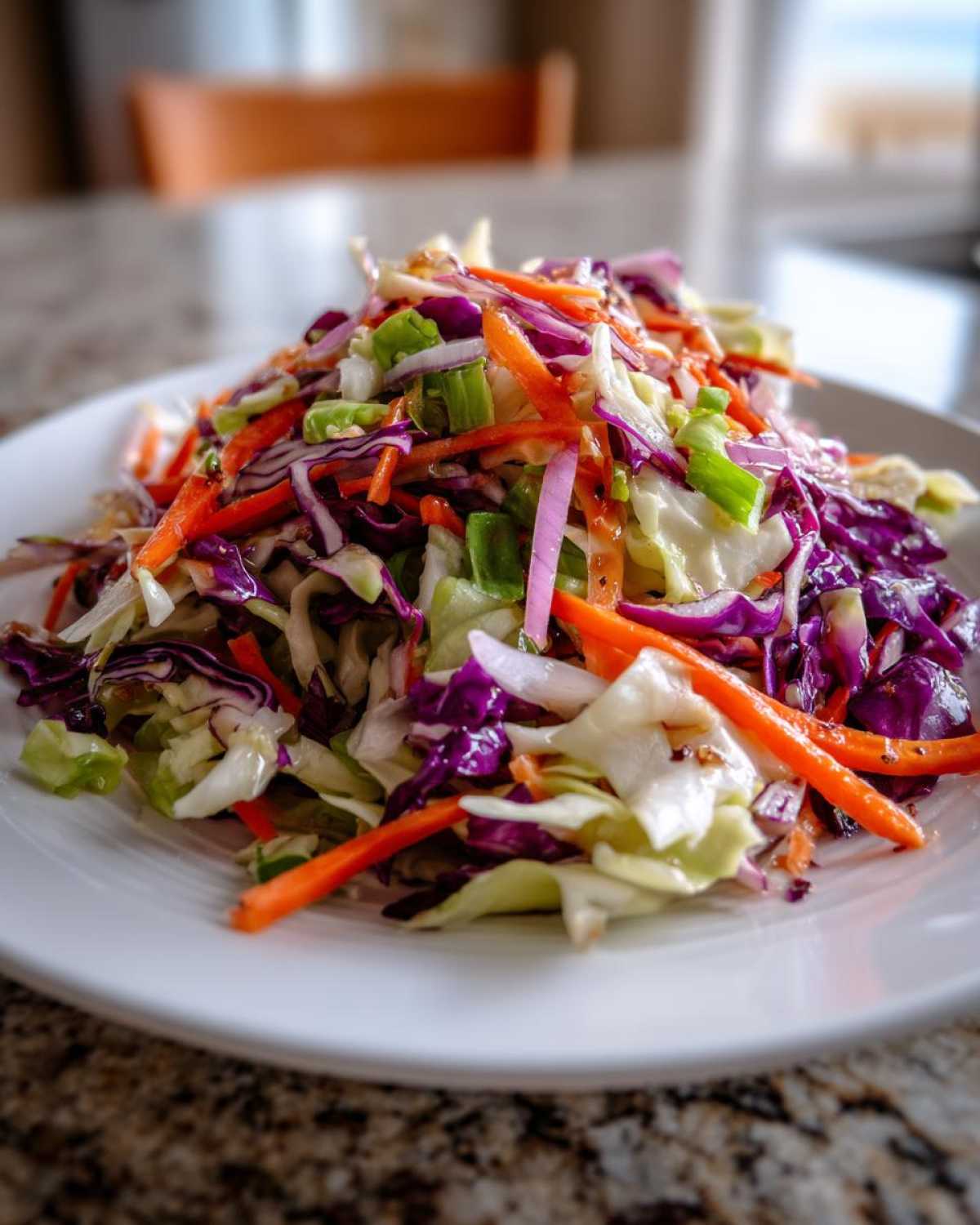 Close-up of a fresh, colorful cabbage salad featuring shredded green and purple cabbage, carrots, and green onions.
