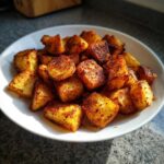 A white plate piled high with golden brown, crispy Air Fryer Crispy Breakfast Potatoes with Paprika.