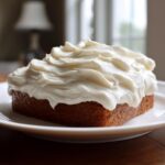 A square piece of baked good generously topped with thick, swirled Copycat Cinnabon Cream Cheese Frosting.