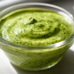 Close-up of vibrant green Copycat Panera Green Goddess Dressing in a small glass bowl.