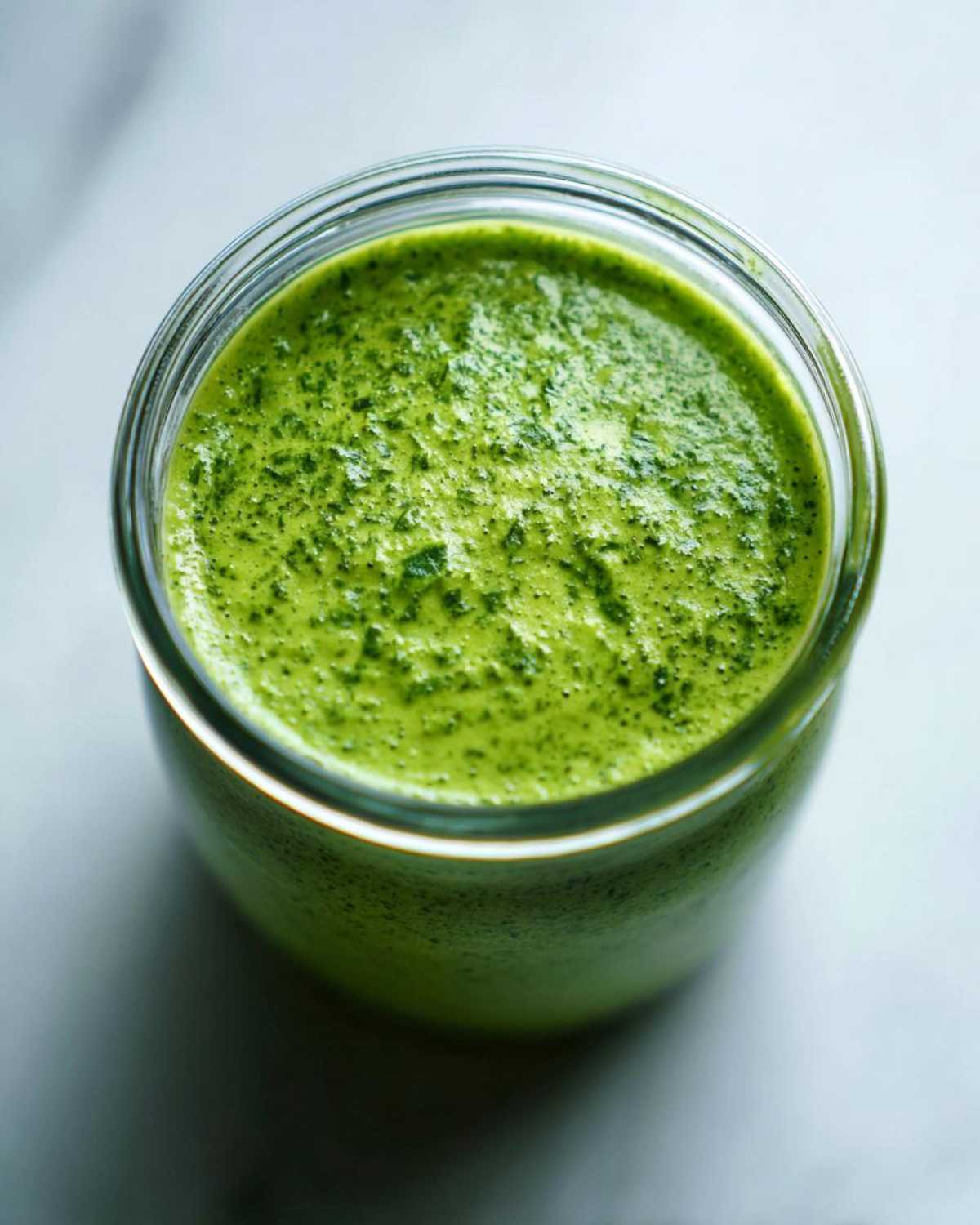Overhead view of vibrant green Copycat Panera Green Goddess Dressing blended smooth in a glass jar.