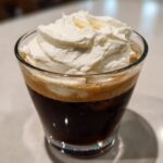 A glass of dark cold brew coffee topped generously with thick, white Copycat Starbucks Vanilla Sweet Cream Cold Foam.