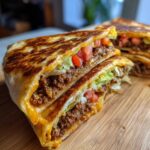 Cross-section of a grilled Copycat Taco Bell Crunchwrap Supreme showing seasoned beef, lettuce, tomatoes, and melted cheese.