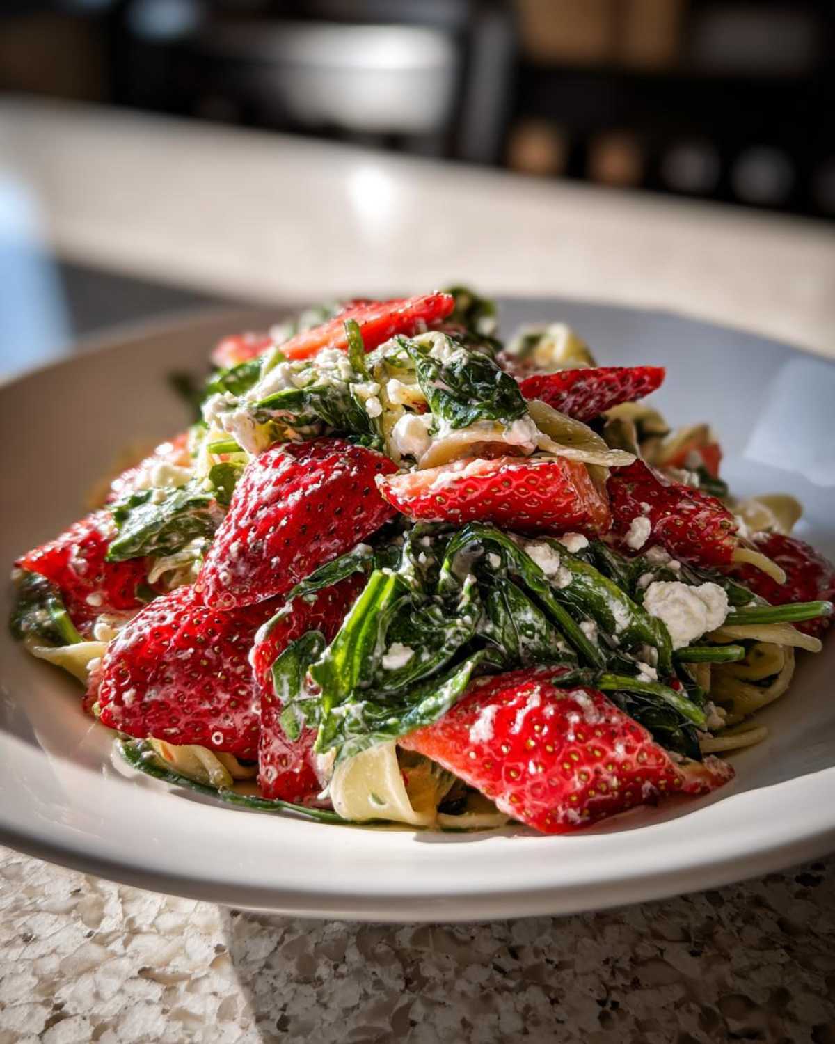 Close-up of Easy Strawberry Spinach Pasta Salad with Feta, featuring bright red strawberries and dark spinach.