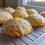 Close-up of freshly baked Gluten-Free Lemon Ricotta Cookies topped with white glaze and lemon zest on a cooling rack.