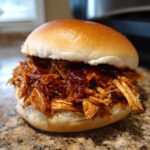 A close-up of a delicious Instant Pot BBQ Pulled Chicken sandwich on a brioche bun.