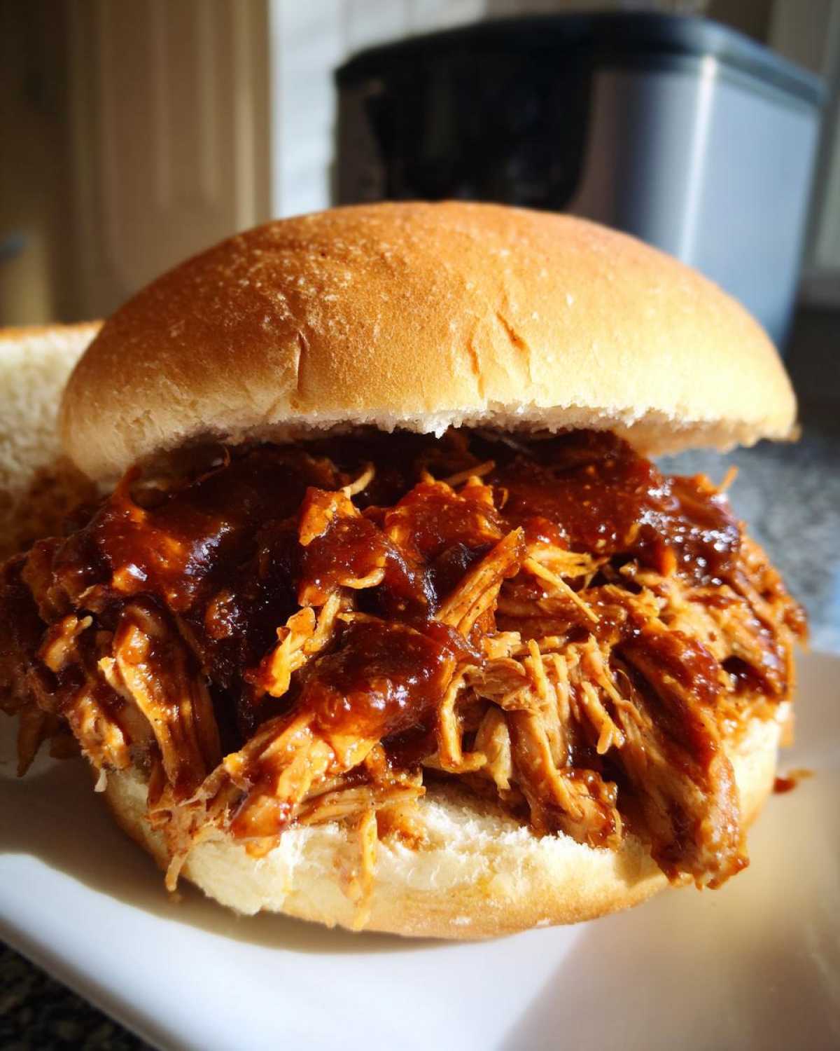 Close-up of a delicious Instant Pot BBQ Pulled Chicken sandwich piled high on a soft bun.