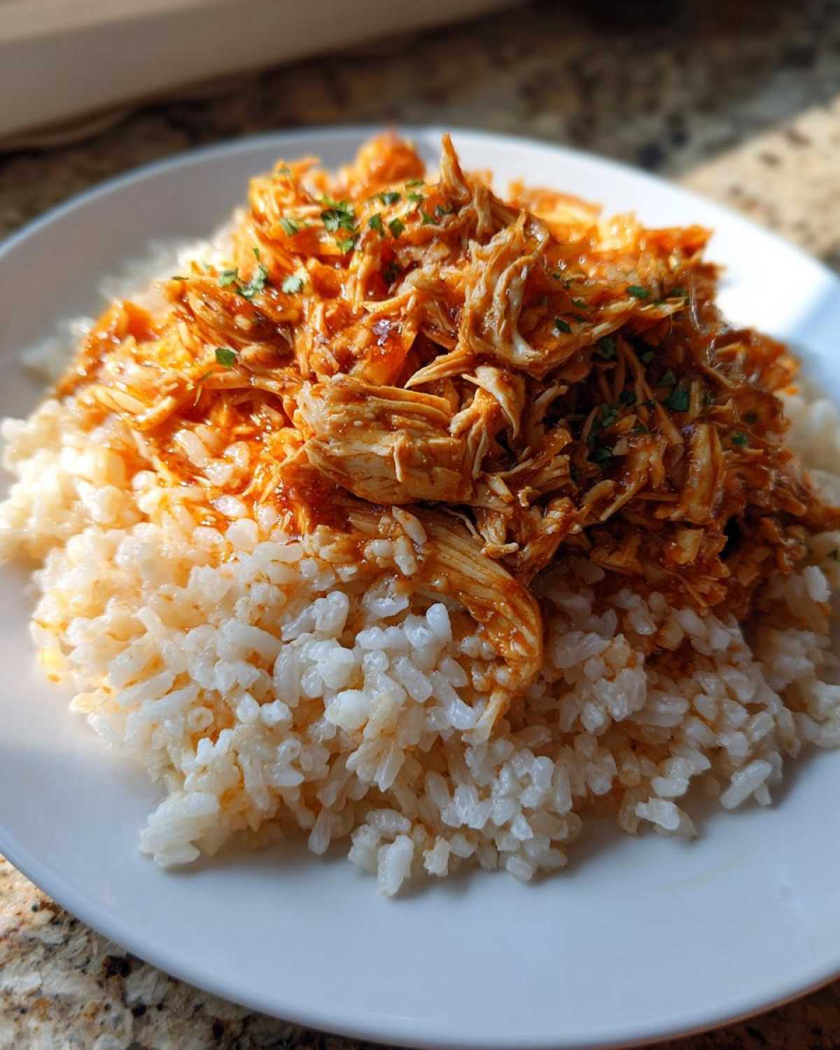 Close-up of saucy shredded chicken served over a bed of brown rice, part of Instant Pot Chicken Burrito Bowls.