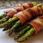 Close-up of perfectly cooked Keto Bacon Wrapped Asparagus Bundles seasoned with pepper.