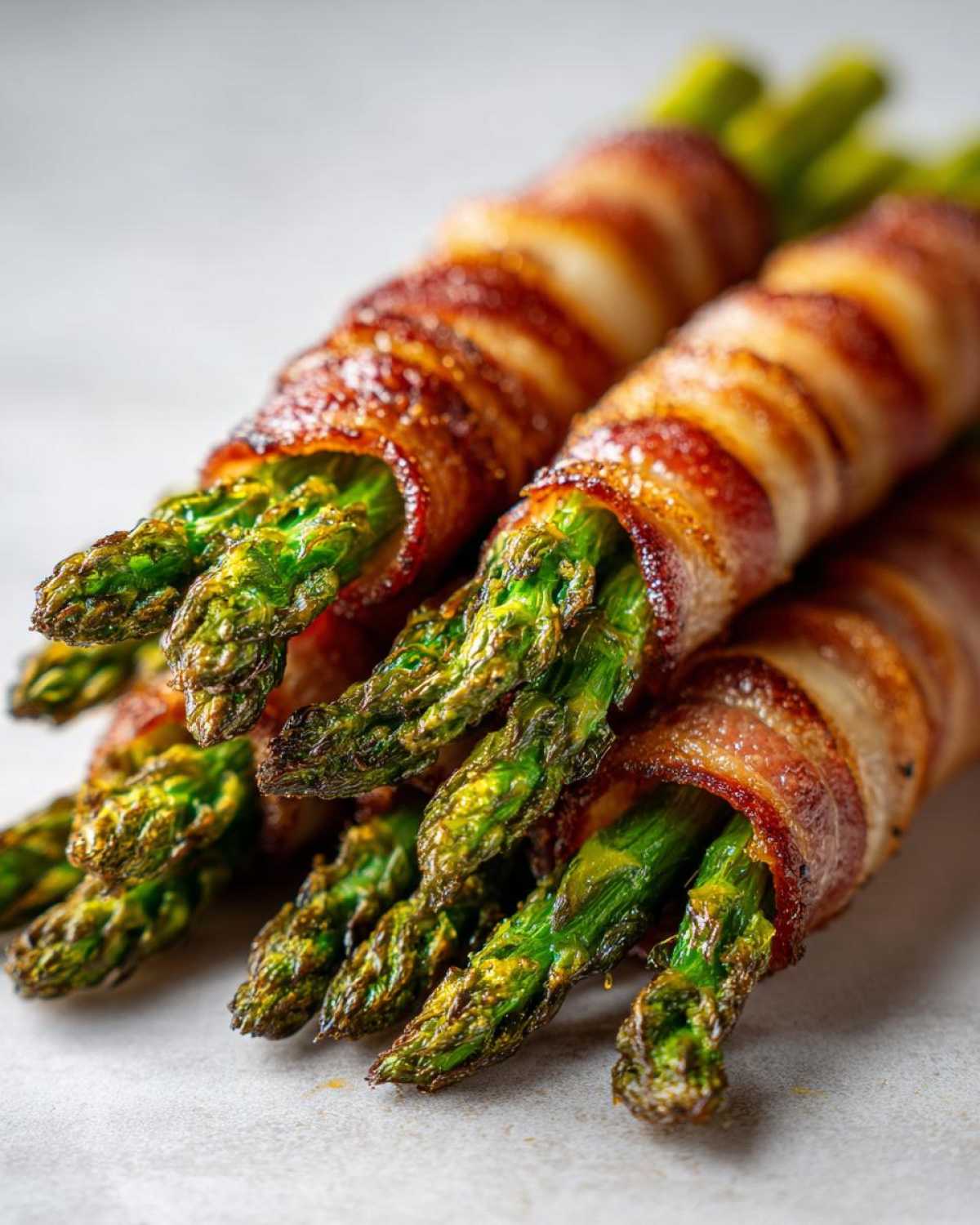 Close-up of perfectly cooked Keto Bacon Wrapped Asparagus Bundles with crispy bacon and bright green tips.