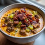 Close-up of a bowl of creamy Keto Cheeseburger Soup loaded with ground beef, pickles, and crispy bacon.