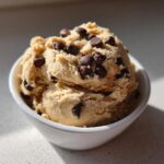 A scoop of creamy Keto Chocolate Chip Cookie Dough Dip topped with mini chocolate chips in a white bowl.