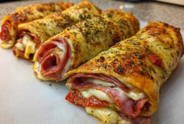 Close-up of three baked Keto Italian Sub Roll-Ups showing melted cheese, pepperoni, and salami filling.