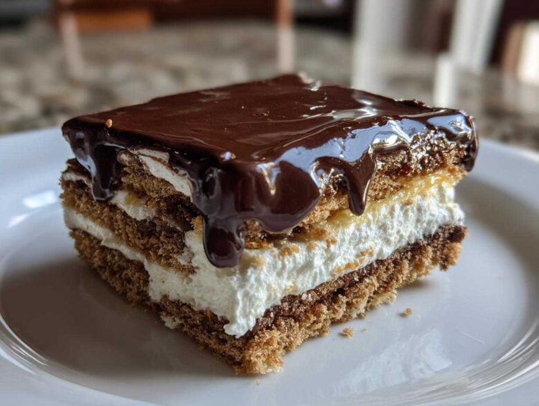 Close-up of a layered slice of No-Bake Chocolate Eclair Cake topped with dripping chocolate ganache.