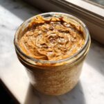 Close-up of creamy Vegan Peanut Butter Banana Overnight Oats topped with swirled peanut butter in a glass jar.