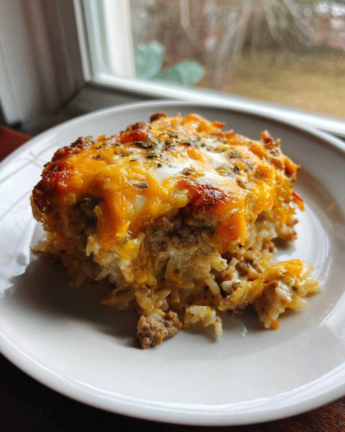 A generous serving of Cheesy Beef and Rice Casserole Comfort Dish topped with melted cheddar cheese.