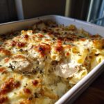 Close-up of a freshly baked Cheesy Chicken Alfredo Bake with browned cheese topping and visible chunks of chicken.