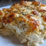 Close-up of a serving of Cheesy Chicken Alfredo Bake showing creamy sauce and browned cheese topping.
