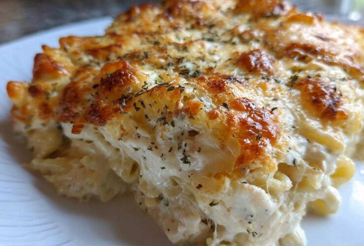 Close-up of a serving of Cheesy Chicken Alfredo Bake showing creamy sauce and browned cheese topping.